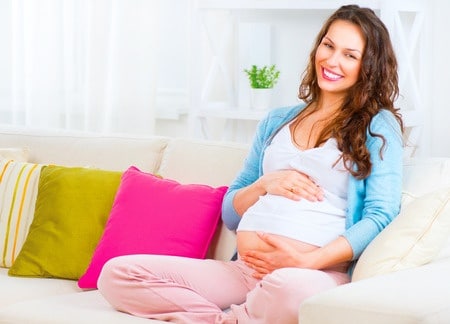 אישה בהריון יושבת ומחייכת, ויטמין סי הכרחי בזמן ההריון לאם ולעובר