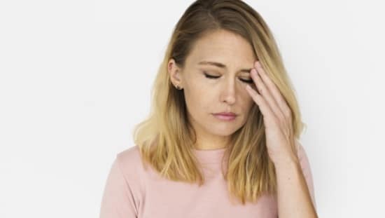 אישה סובלת מכאב בראש, שהוא אחד מכמה תסמינים של לחץ גבוה